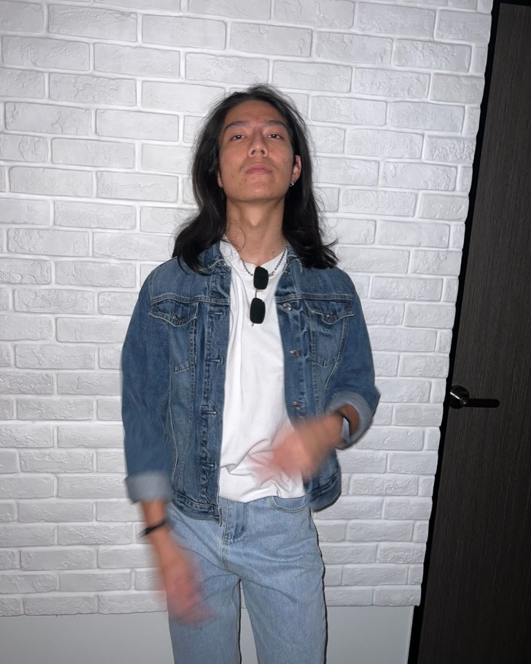 Hongpo in a denim jacket against a brick wall
